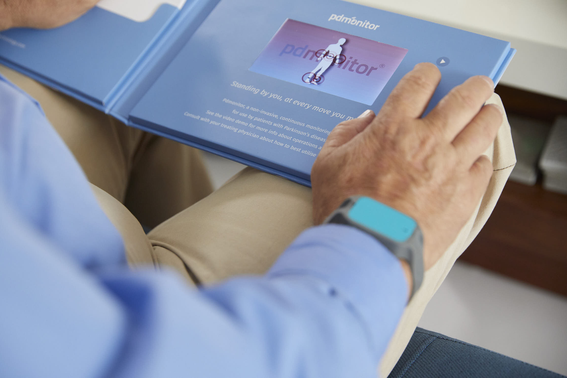 A person reading the PDMonitor setup guide with a sensor on their wrist